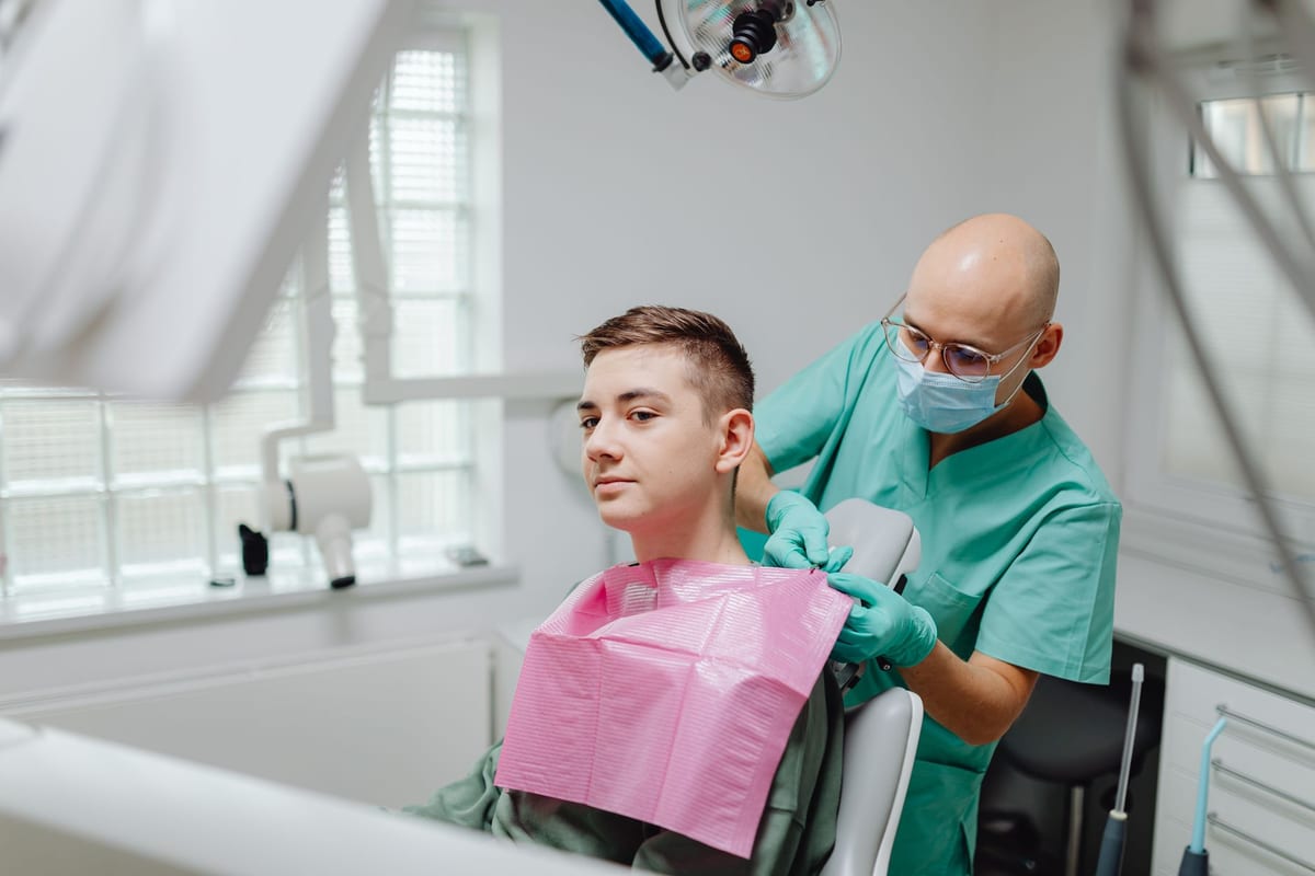 A clinician settling a young patient into the dental chair