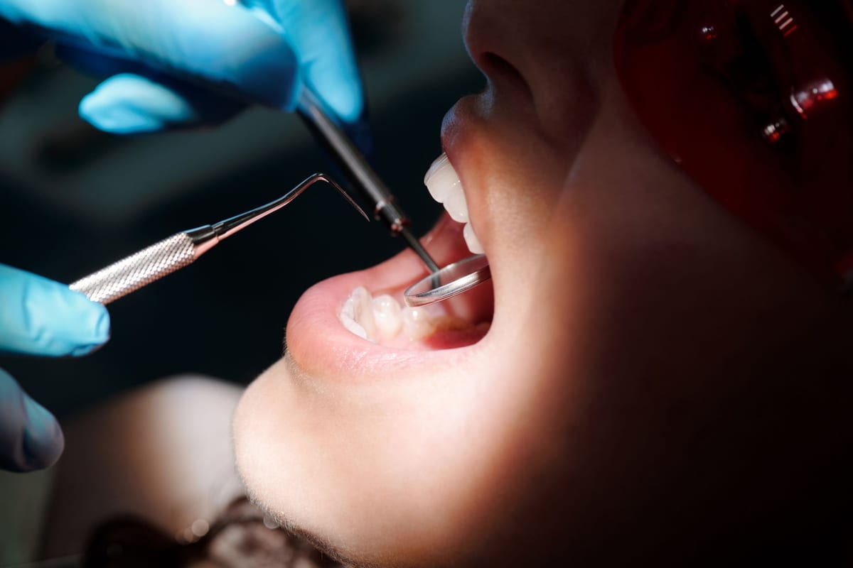 A close view of a dental examination with a mirror and a probe